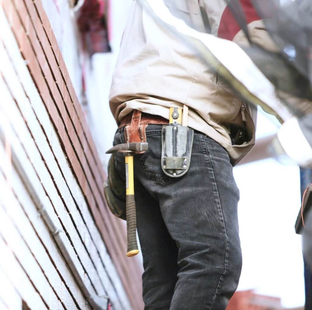 Technicians waist with a tool belt holding a hammer and other tools