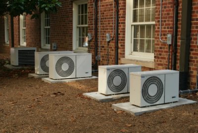 5 air conditioning units in a row outside of red brick building